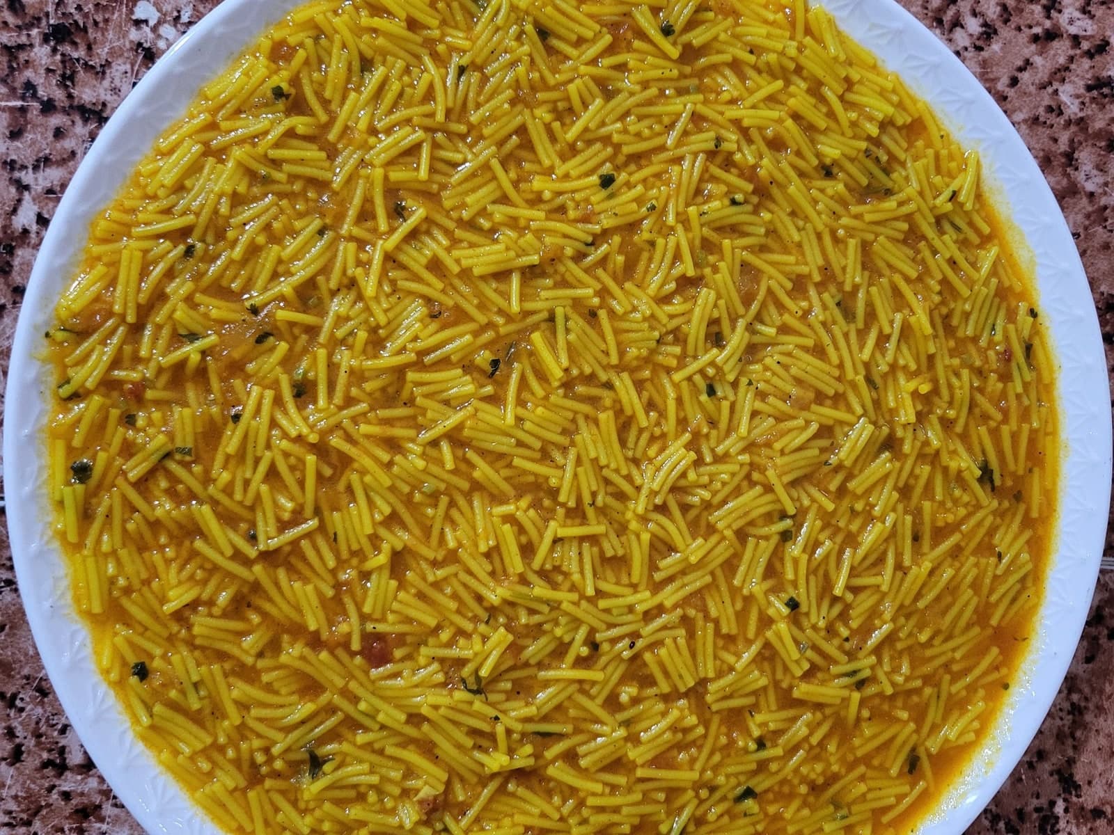 Moroccan chaariya bel matisha — fine vermicelli in a turmeric and tomato sauce, scattered with coriander, in a white dish