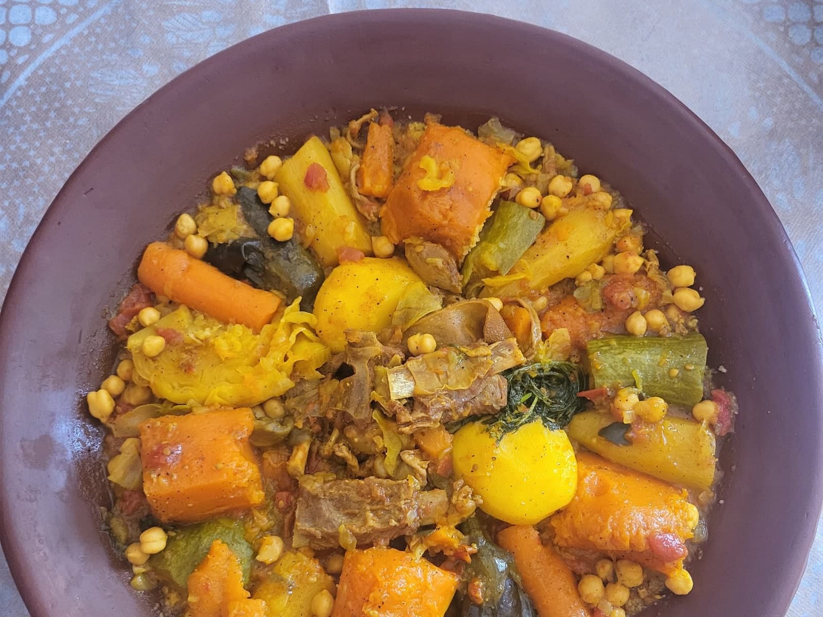 Moroccan couscous with kerdas and kaddid — preserved meat with carrot, pumpkin, courgette, aubergine and chickpeas in a clay dish