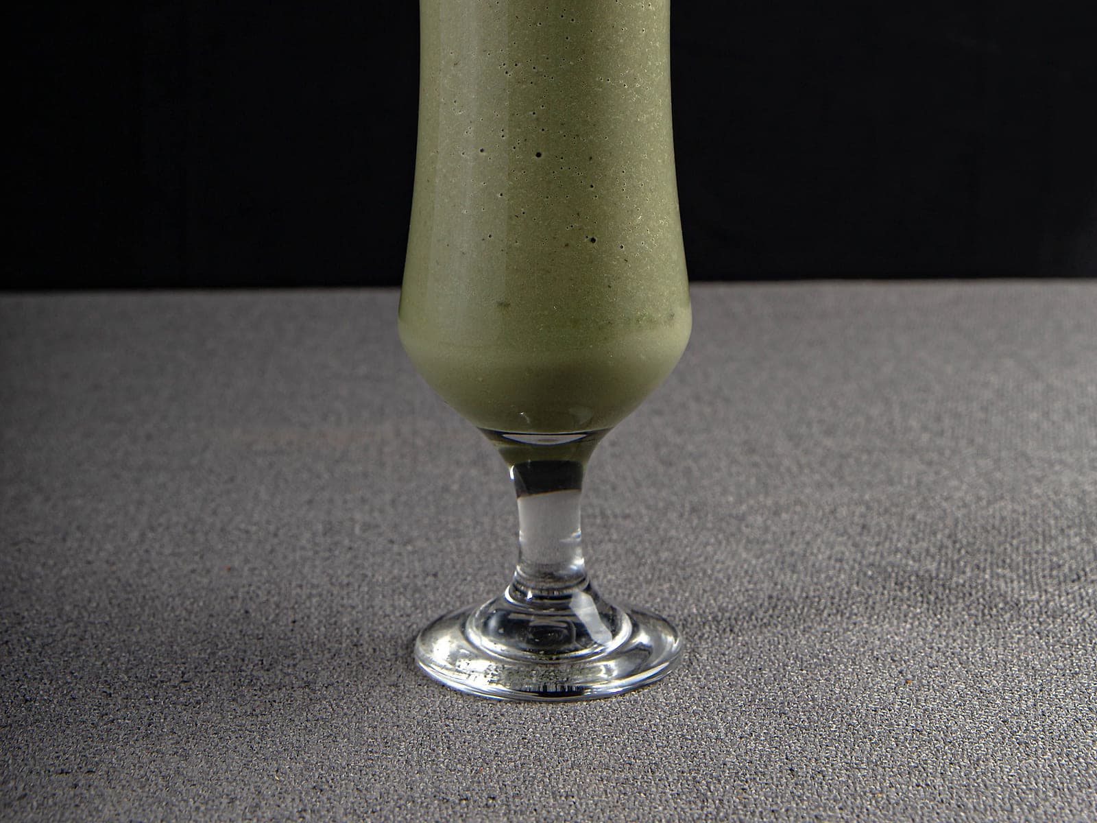 Tall glass of Moroccan avocado smoothie topped with cinnamon and chopped almonds