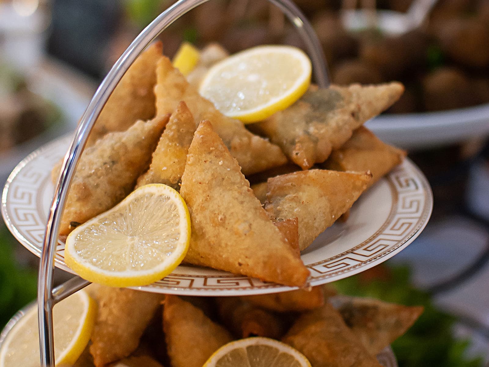 Plate of golden Moroccan briouat pastry triangles drizzled with honey and sesame